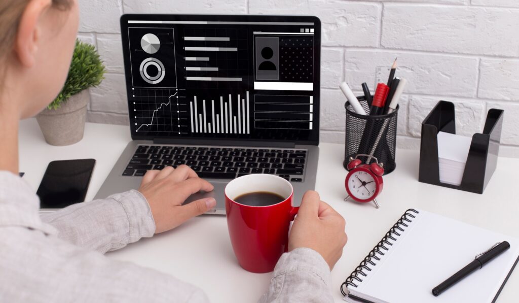 Female financial analyst working on laptop at office, studying statistics graphs